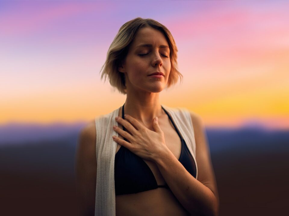 Mujer respirando con calma, con los ojos cerrados y la mano en el pecho