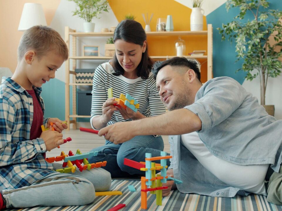 Madre, padre e hijo jugando juntos con bloques de colores en casa